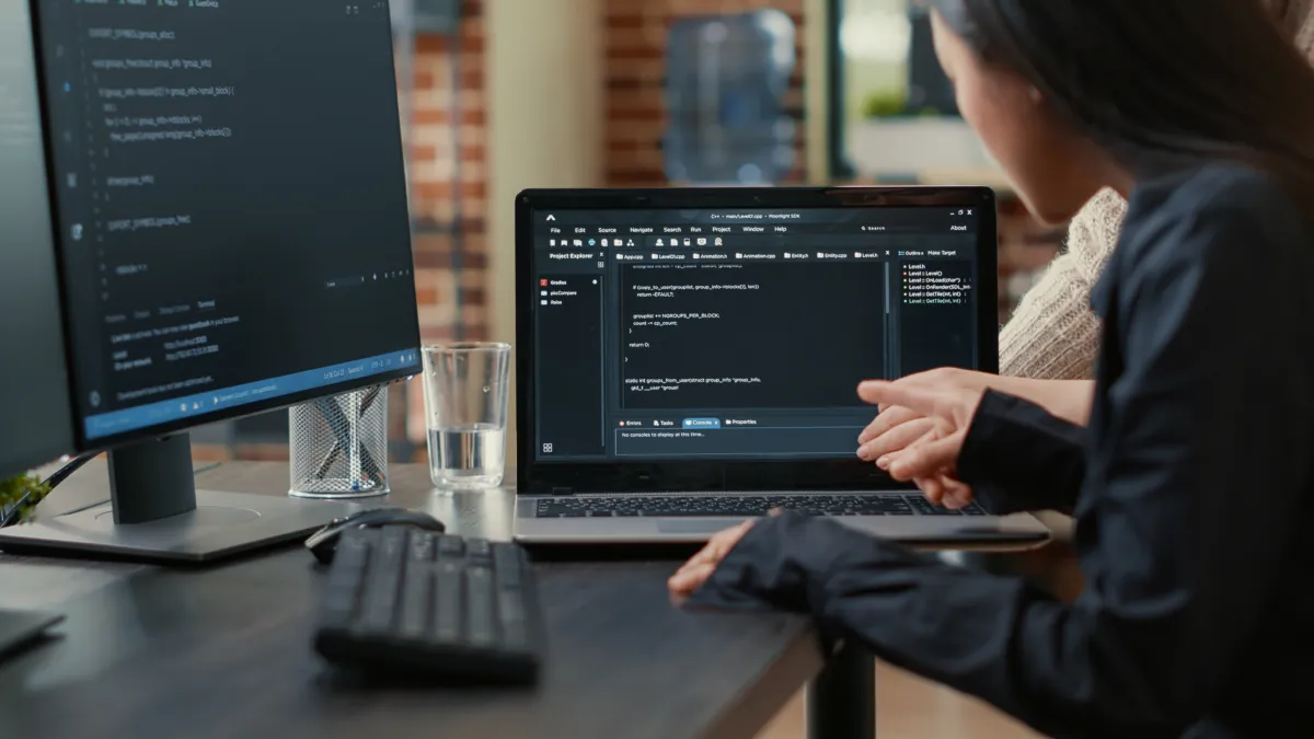 Team programmers talking about algorithm running laptop screen pointing source code while sitting desk software developers collaborating data coding group project