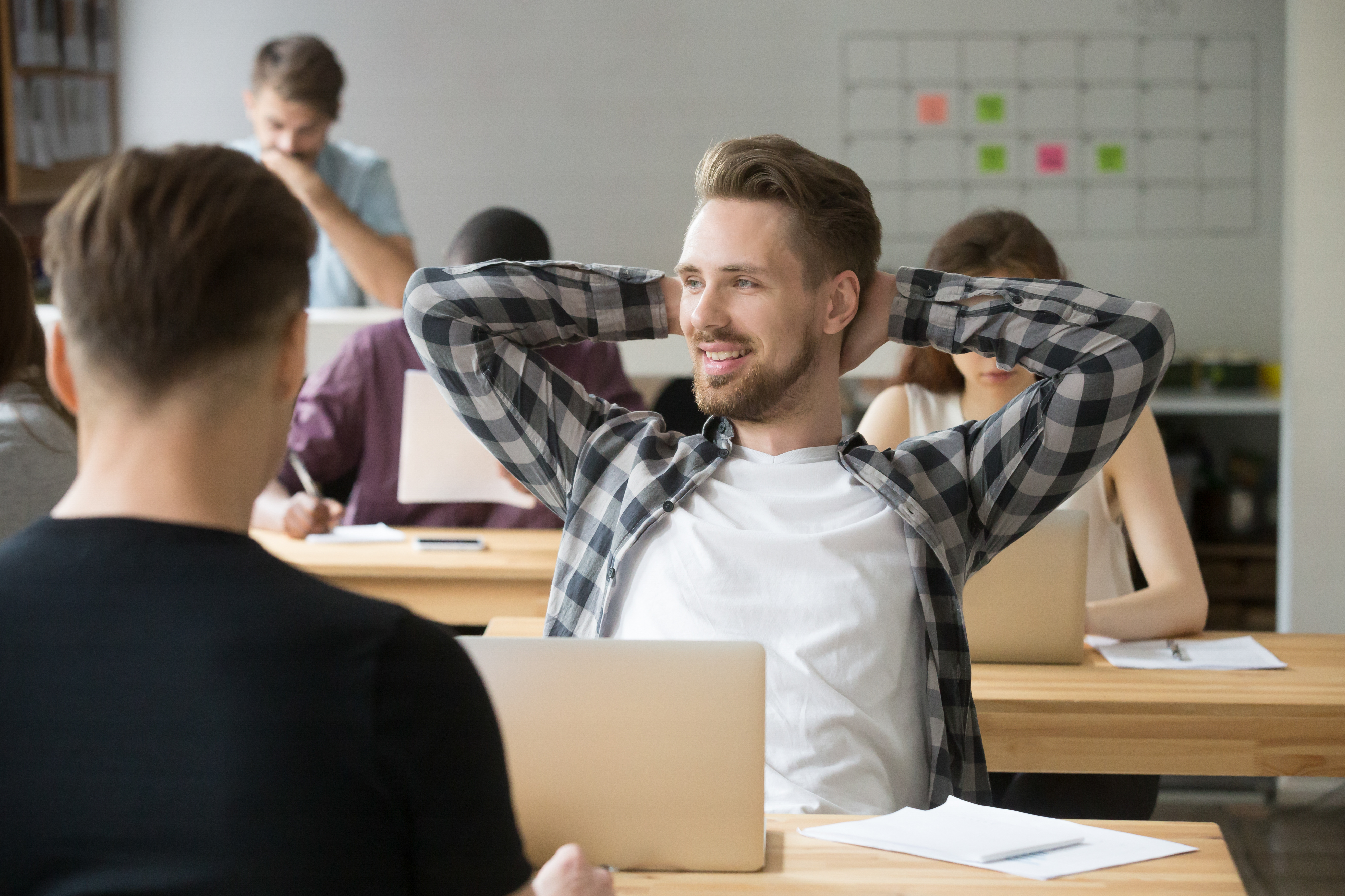 Smiling man relaxing hands head enjoying work co working